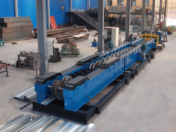 A long, blue Fully Automatic Cable Tray Production Line is shown in a factory workshop. The machine features multiple roller stations and is processing a metal profile, with finished cable trays visible on the floor.