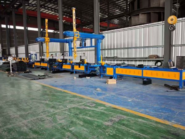 A full view of a long CZ purlin making machine production line inside a large factory. The machine is painted blue and yellow and features multiple automated arms and processing sections, stretching across the factory floor.