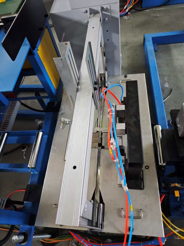 A close-up view of the packing section of a Fully automatic light steel keel machine, showing a formed light steel keel positioned within the mechanism, surrounded by pneumatic tubes and metal guides.