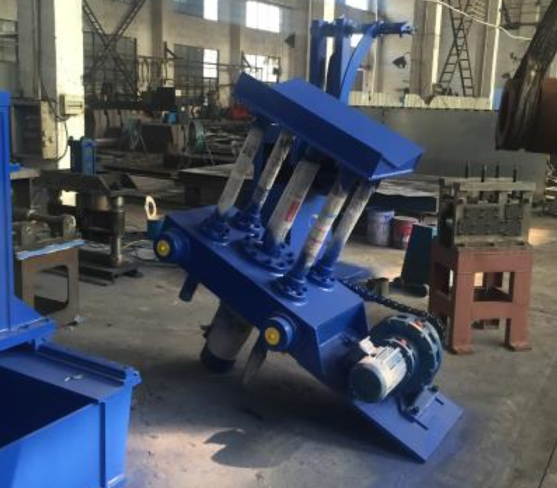 A blue hydraulic entry coil car for a slitting line, featuring multiple hydraulic cylinders and a chain-driven motor assembly, shown in a factory setting.