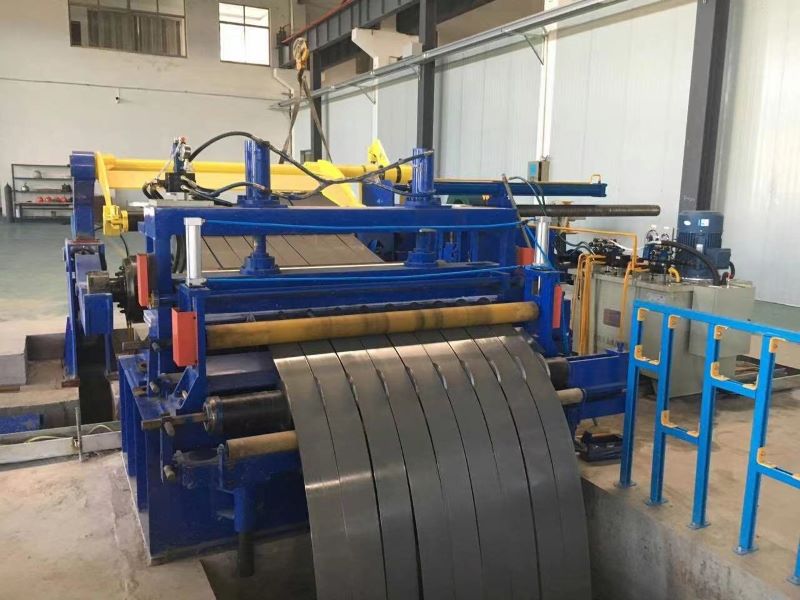 The slitter section of a hydraulic slitting line, where a wide steel coil is being cut into multiple narrower strips by circular blades.