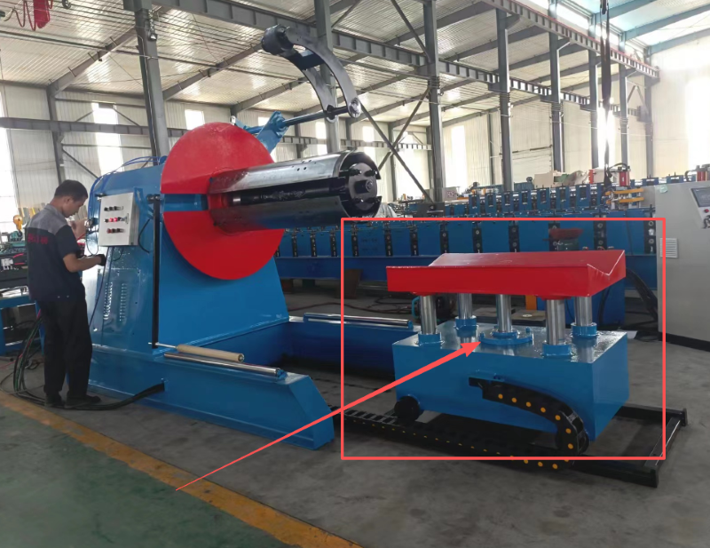 A 5 guide column cart positioned on a track in front of a blue hydraulic decoiler in a factory setting.