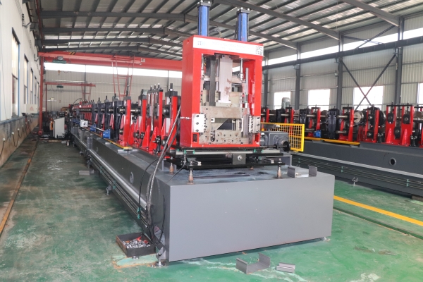 A long industrial CZ purlin making machine with a red forming section and a grey base, located in a factory workshop.