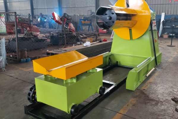 Hydraulic decoiler with loading car, showing the main machine body and mobile cart for coil handling.