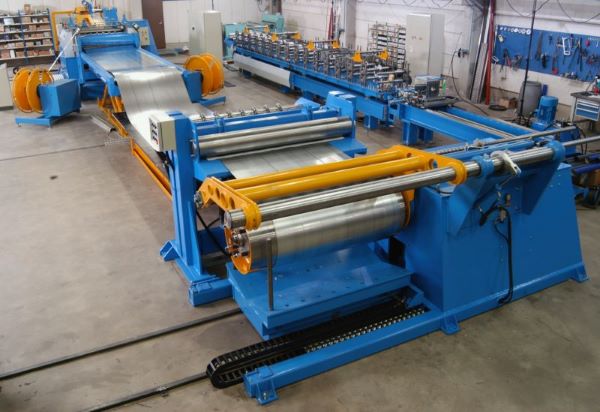 Hydraulic slitting line in operation, showing the uncoiling, slitting, and recoiling sections with steel strip running through the machine.