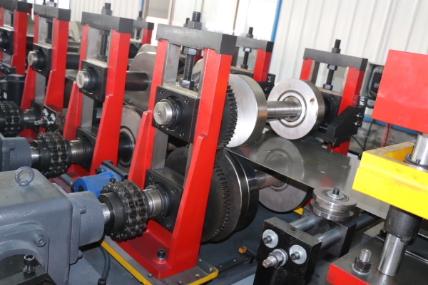 Roll forming section of the CZ purlin making machine with multiple red stands and drive chains.