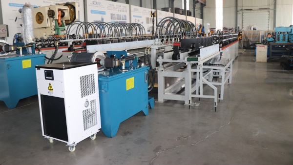 T-Bar Roll Forming Machine setup in a factory, featuring a white industrial chiller unit and blue hydraulic power pack.