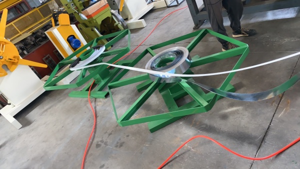 Horizontal decoiler with metal coils mounted on green steel frames, feeding strips into the T-Bar roll forming machine.