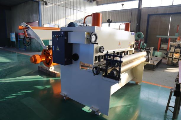 White and orange hydraulic cutter unit, part of a hydraulic slitting line, designed to shear steel plates before slitting.