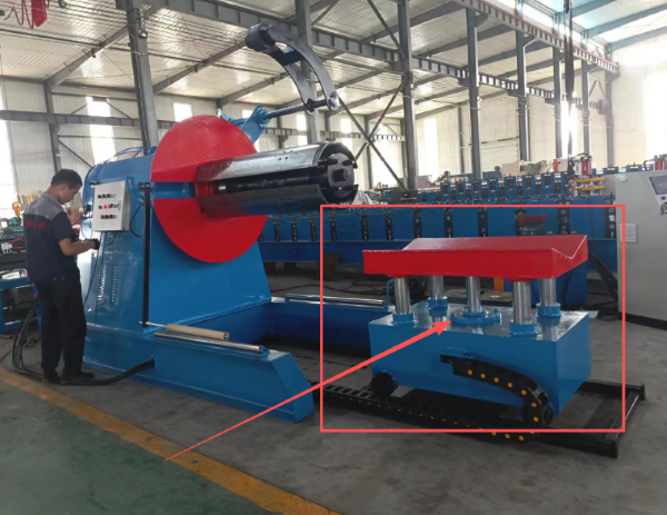 A worker operates a blue hydraulic de-coiler in a factory; a red-framed inset highlights a heavy-duty loading cart with five vertical guide columns and a blue base, designed to support heavy coils without tilting.